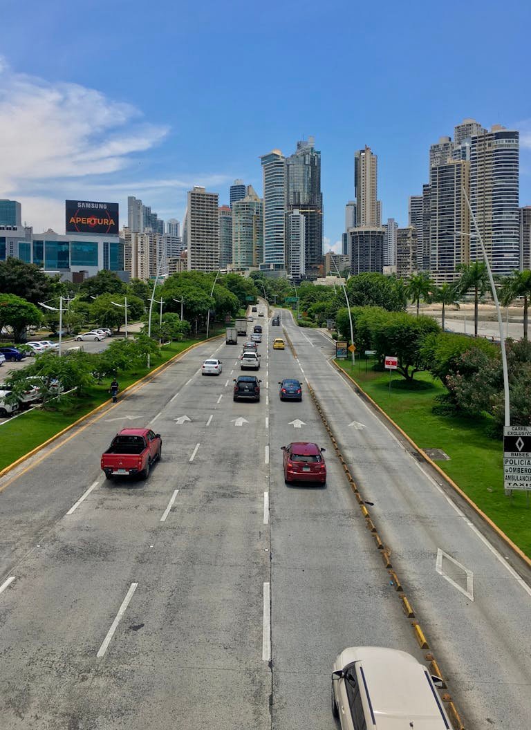 Dynamic aerial view showcasing Panama City's skyline and bustling highway under a clear blue sky.